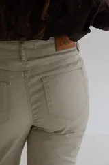 Pantalón de tiro alto con acabado engomado, de corte recto y pierna con leve apertura. Presenta cierre frontal con botón y bolsillos laterales.
