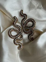 Aros colgantes con forma de serpiente blanca delineada con strass plateado.