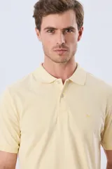 Remera polo piqué de algodón color amarillo, con cuello y puños acanalados, y cierre frontal de botones.