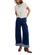 Pantalón de jean ancho de tiro alto, color azul oscuro, con pliegues pronunciados en la parte delantera y puños doblados en el ruedo.