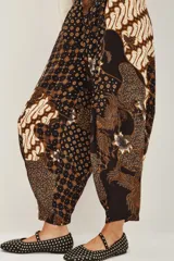 Pantalon de corte holgado tipo bombacho con estampado batik tradicional en tonos azul marino, beige y dorado. Presenta cintura elástica y diseño fluido.