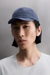 Gorra deportiva de tejido técnico ligero en color azul marino, con visera corta y paneles laterales perforados para mayor ventilación. Presenta logos bordados a tono en el frente.