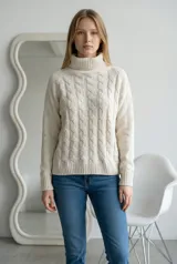 Sweater de cuello alto tipo polera, confeccionado en tejido de chenille con textura suave y diseño de trenzas verticales en el frente. Posee mangas largas con puños acanalados y ruedo también acanalado.