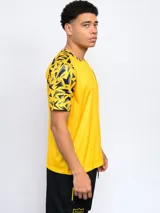 Remera deportiva de hombre, color negro, con cuello redondo y mangas cortas con estampado geométrico en amarillo y gris. Lleva el escudo de Peñarol en el pecho.