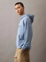 Buzo con capucha celeste de algodón con logo Calvin Klein estampado en el pecho. Tiene bolsillo tipo canguro, puños y dobladillo acanalados, y corte relaxed.