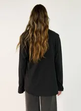 Blusa de manga larga en color blanco, con cuello redondo y detalle de alforzas verticales en el frente. Presenta un corte holgado y fluido.