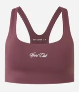 Top deportivo de microfibra color ciruela, con escote cuadrado frontal y espalda tipo nadador. Presenta un pequeño logo bordado en blanco en el centro del pecho.
