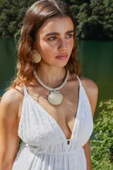 Set de accesorios compuesto por un collar de soga trenzada con dije central de concha marina dorada y un par de aros a juego con diseño de concha marina dorada.