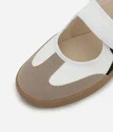 Championes estilo chutera de mujer, con diseño de punta redonda y cierre de velcro. Presenta una combinación de colores blanco, beige y negro con recortes contrastantes y suela plana color caramelo.