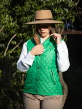 Chaleco capitoneado color rosa claro, con cuello alto, cierre frontal con botones a presión y logo bordado en el pecho.