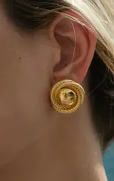 Par de aros dorados con forma circular y diseño trenzado alrededor de una esfera central.