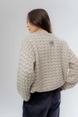 Buzo de punto grueso con diseño bicolor en patrón geométrico, de calce holgado y mangas largas.