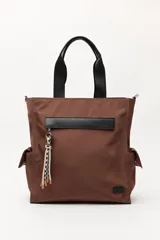 Bolso tipo tote color negro, con doble asa superior y correa desmontable. Presenta un bolsillo frontal con solapa, bolsillos laterales y un detalle colgante decorativo con tiras de colores.