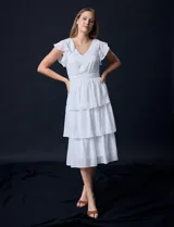 Vestido blanco de gasa con capas, marca Julia Jordan. Escote en V, manga corta con volados, corte en cintura y abertura central en espalda con cierre invisible.