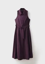 Vestido midi de corte evasé en color violeta oscuro, con cuello camisero, sin mangas y cierre frontal con botones. Incluye un cinturón ajustable a tono que marca la cintura.