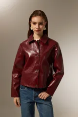 Chaqueta de eco-cuero color bordó, con cuello camisero, cierre frontal con botones y mangas largas.