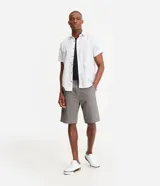 Bermuda masculina de corte recto confeccionada en sarga de algodón. Presenta cierre frontal con botón y cremallera, bolsillos laterales y traseros, y diseño liso sin estampados.
