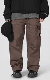 Pantalón cargo marrón de calce regular, confeccionado en textil técnico pesado. Posee cintura con cordón ajustable, bolsillos cargo de gran tamaño en los laterales y puños ajustables con tancas en los tobillos.