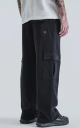 Pantalón tipo jogger de calce baggy con silueta amplia y relajada, confeccionado en frisa pesada de algodón. Cuenta con cintura elástica, bolsillos laterales de mano y bolsillos estilo cargo con solapa y cierre.