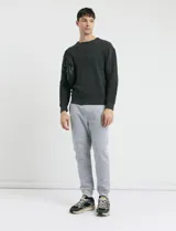 Sweater de punto en color negro, con cuello redondo, mangas largas y puños acanalados.