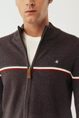 Campera tejida color verde militar, con cuello alto, cierre frontal completo, logo bordado en el pecho y rayas horizontales en blanco, marrón y azul marino.