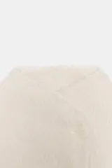 Cazadora de textura suave efecto pelo, color crudo, con cuello subido y cierre frontal cruzado con botones. Presenta mangas largas y bolsillos laterales ocultos en las costuras.