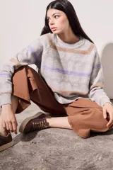 Sweater gris melange de punto con cuello redondo y mangas largas. Presenta rayas horizontales en tonos marrón y lila.