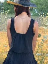 Top negro de tirantes finos con escote decorado con encaje y lazos frontales ajustables. Presenta una silueta liviana y femenina con diseño fluido.