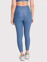 Calza deportiva de tiro alto con cintura en forma de V, confeccionada en tela brillante de efecto segunda piel. Presenta un diseño liso y ajuste regular.