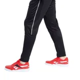Pantalón de jogging negro con dos líneas blancas verticales a los costados y logo de Reebok bordado en blanco.