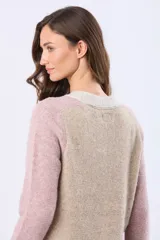 Saco tipo cárdigan de tejido grueso con diseño en bloques de color, combinando tonos beige y rosado. Presenta cuello en V, cierre frontal con botones y dos bolsillos delanteros.