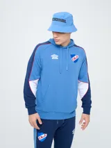 Canguro deportivo Umbro del Club Nacional de Football, modelo Nexo para hombre. Diseño en color azul marino con mangas rojas y detalles en celeste y blanco, capucha con cordón ajustable y bolsillo tipo canguro.