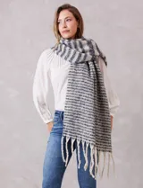 Bufandón de tejido soft con diseño de rayas horizontales en tonos gris y blanco, con terminación de flecos largos en los extremos.