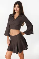 Minifalda color marrón oscuro, confeccionada en lino italiano, con diseño de cintura baja con caderín y bajo acampanado. Cierre invisible en el lateral.