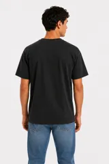 Remera de manga corta color azul marino, con cuello redondo y diseño holgado. Presenta un pequeño texto sutil estampado en el centro del pecho.