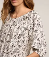 Blusa blanca con estampado floral negro, escote hombro a hombro y mangas 3/4 abullonadas.