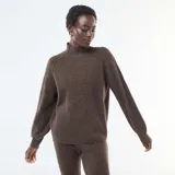 Sweater de punto canalé en color marrón, con cuello alto y mangas largas con puños ajustados. Presenta un diseño de corte holgado y tejido texturizado.