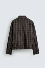Cazadora de corte cropped confeccionada en algodón con estampado de cuadros. Presenta cuello solapa, cierre frontal con cremallera, mangas largas con puños abotonados y bolsillos frontales de plastrón. El bajo es ajustable mediante cordón.