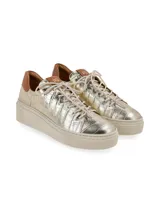 Sneaker de cuero con acabado metalizado dorado y textura croco, suela plataforma de goma en tono tostado y detalle marrón en el talón.