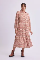 Vestido camisero midi color marrón con estampado geométrico en blanco, de corte recto, con cuello camisero, abotonadura frontal y mangas largas con puños abotonados.