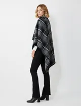 Capa de tejido cuadrille con diseño de cuadros en tonos marrón, beige y naranja. Presenta un cierre frontal con botón tipo trenca y bordes con ribete negro.