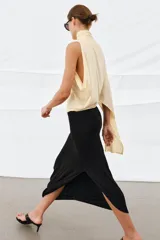 Top color amarillo claro con cuello alto, mangas asimétricas y bajo recto.