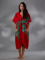 Capullo o kimono de paño 100% algodón, color rojo con estampado exclusivo en tono verde, de morfología amplia y envolvente, con bolsillos laterales y cinto independiente para ajustar la cintura.