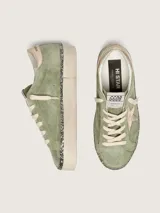 Zapatillas Hi Star de Golden Goose con empeine de gamuza verde militar, estrella lateral y contrafuerte en cuero metalizado dorado, plataforma alta con canto revestido en glitter y cordones de algodón crudo.