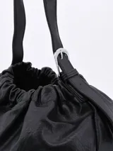 Morral negro de cuero sintético con fruncido superior y correa larga regulable.
