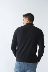 Buzo de algodón con cuello alto y cierre frontal parcial. Presenta puños y ruedo acanalados, con un pequeño logo bordado en el pecho.