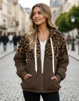 Campera tipo polar con cierre frontal, diseño combinado con estampado animal print en la parte superior y tejido de peluche blanco en la parte inferior. Cuenta con capucha con cordones ajustables y dos bolsillos frontales.