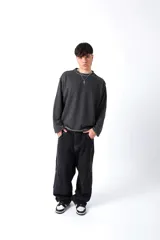 Buzo gris oscuro, estilo sweatshirt, con cuello redondo y terminaciones al corte en cuello, puños y cintura. Presenta un bordado en el frente.