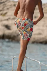 Short de baño Von Braun con estampado tropical de hojas y círculos en tonos rojos, amarillos y verdes sobre fondo claro. Cuenta con cintura elástica, dos bolsillos laterales, un bolsillo trasero con cierre y etiqueta de la marca.