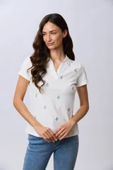 Remera polo blanca de algodón de manga corta, con cuello en V y delicados mini bordados florales distribuidos en la prenda.